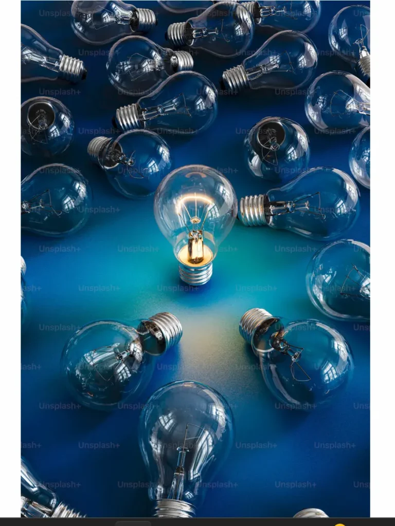 A single illuminated light bulb standing out among unlit bulbs on a blue background, symbolizing innovation, leadership, and breakthrough thinking